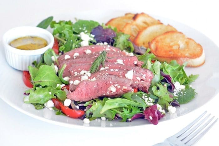 Steak salad on a white plate.