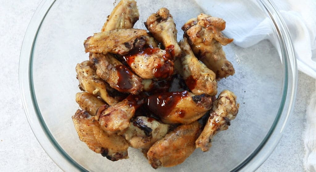 Sauce poured on chicken in a glass bowl.