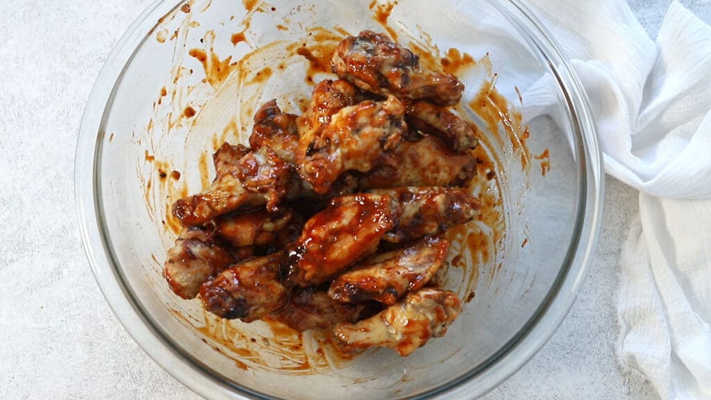 poultry tossed in a spicy sauce in a glass bowl.