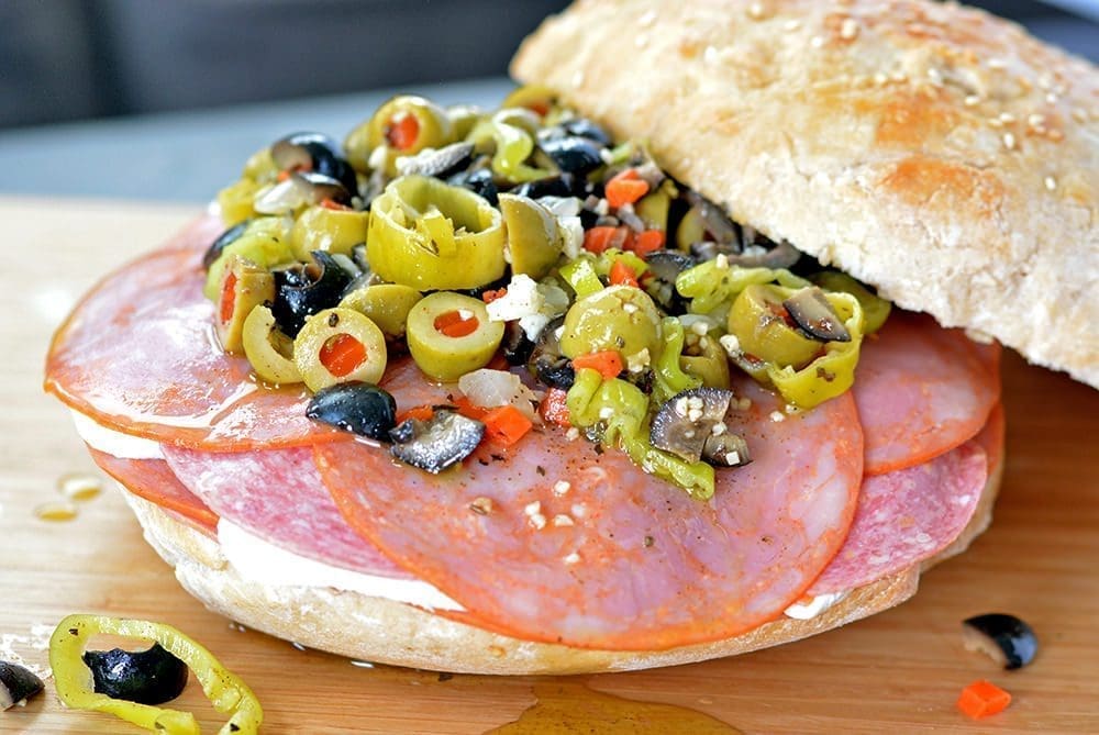 Muffuletta topped with olive salad and bread.