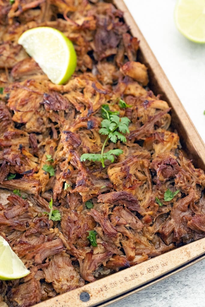 Tray of Authentic Carnitas with lime wedges.