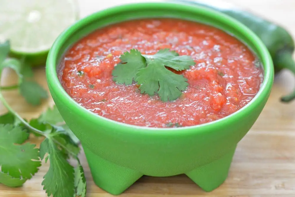Homemade salsa in a small green bowl with cilantro.