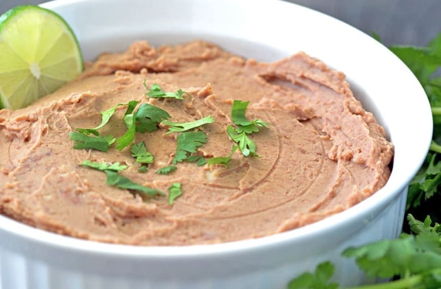 Refried beans in a white bowl.