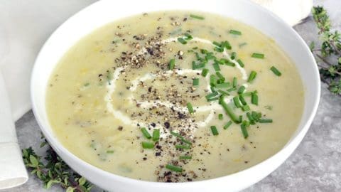 Potato and Leek Soup in a white bowl garnished with chives.