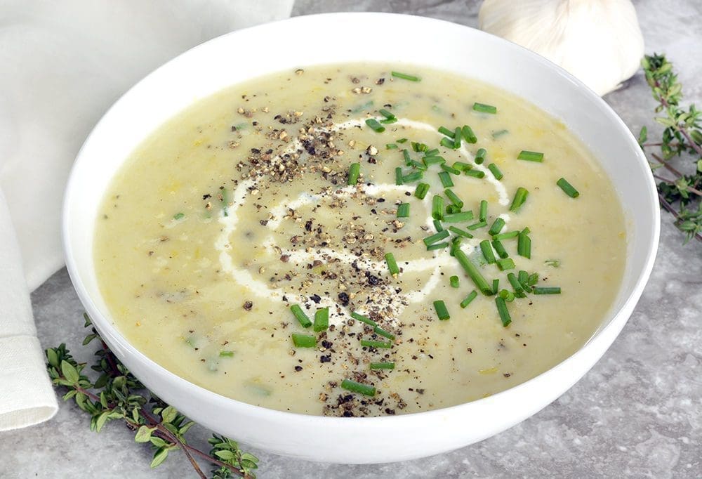 Potato and Leek Soup in a white bowl garnished with chives.