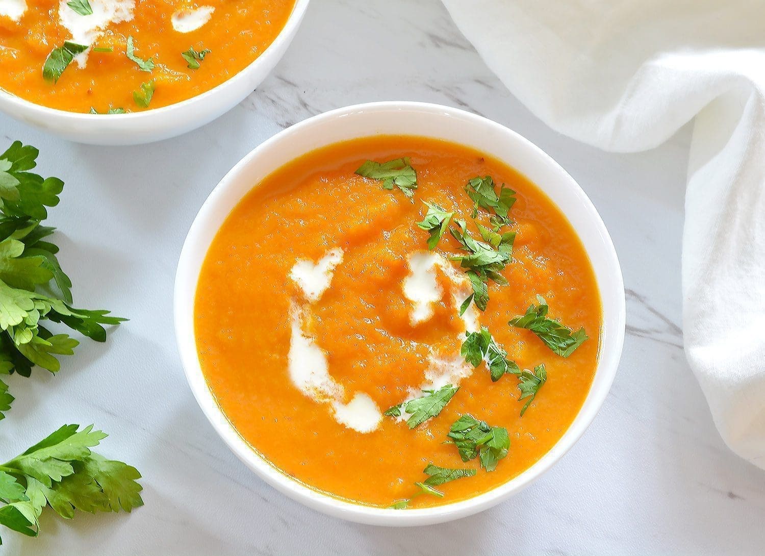 Two bowls of Carrot Ginger Soup topped with parsley