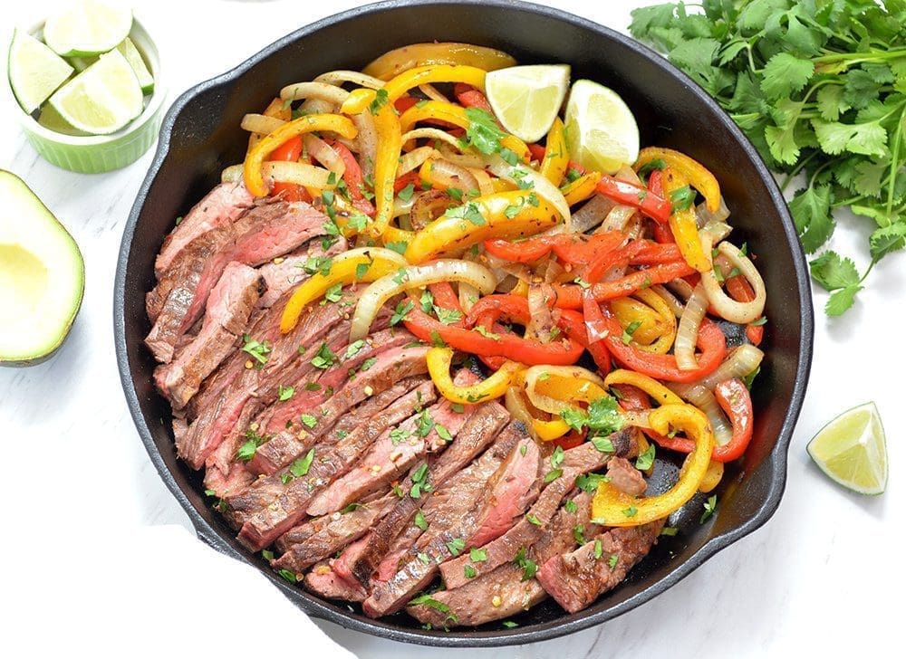 Steak Fajitas and onions and peppers in a black cast iron pan