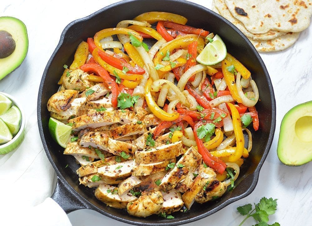Chicken Fajitas with bell peppers and onions in a black cast iron pan