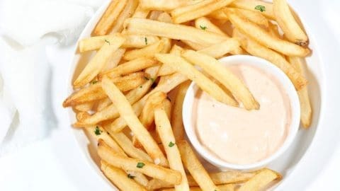 white Plate of air fried frozen french fries with chipotle mayo dipping sauce on the side.