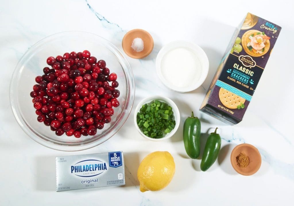 Ingredients to make cranberry jalapeno dip: cranberries, cream cheese, lemon, green onions, jalapenos, spices and crackers