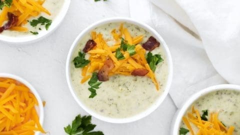 three white bowls filled with Irish Potato Soup topped with cheese and bacon.