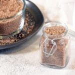 BBQ Rub in a clear container. A large batch is in the background in a clear bowl on a black plate.