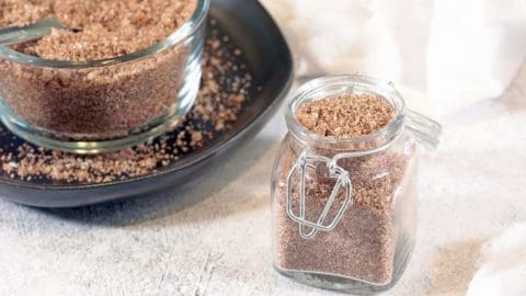 BBQ Rub in a clear container. A large batch is in the background in a clear bowl on a black plate.