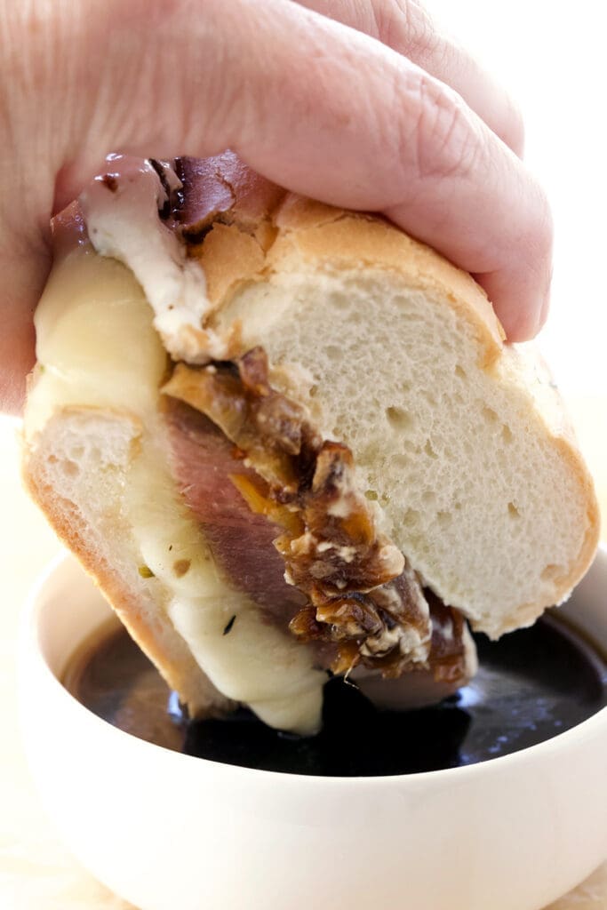 Dip the sandwich into the au jus by hand.