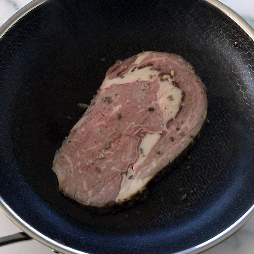 Slices of prime rib warming in a black skillet.