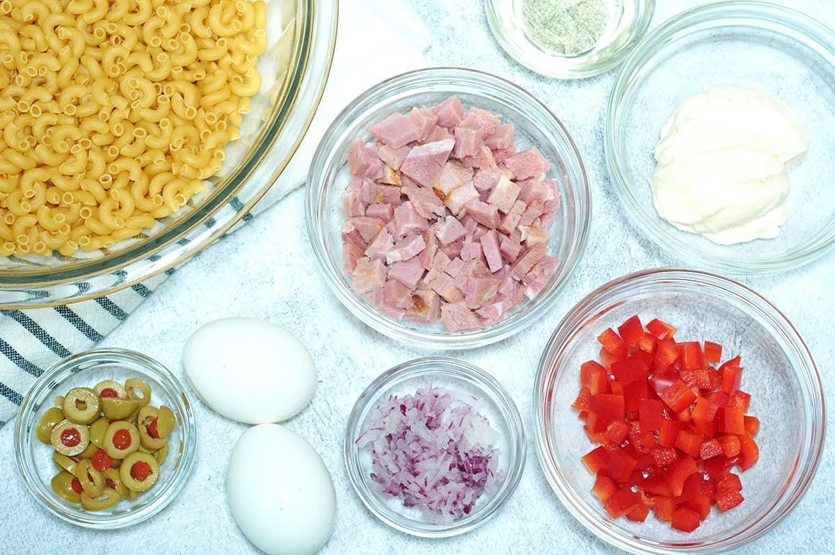 Ingredients for ensalada de coditos separated out in clear bowls.