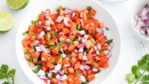 Pico de Gallo in a white bowl surrounded by the individual ingredients.
