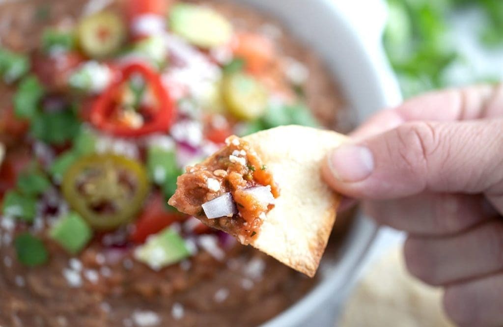 An air fryer tortilla tip with bean dip held near the camera.