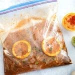 Flank steak marinating with orange slices in a Ziploc Bag for how to tenderize beef article.