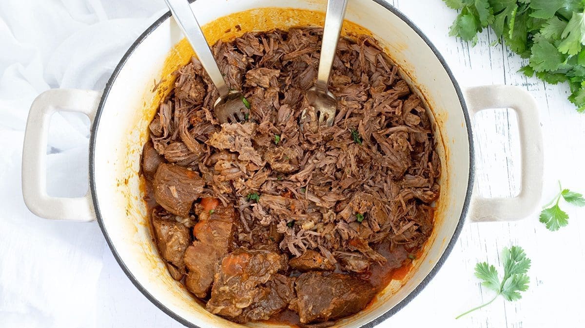 Shredded meat in a cream dutch oven.