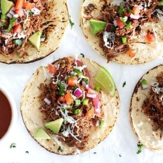 Four birria tacos on parchment paper supporting what to serve with tacos guide.