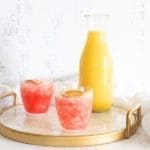 Jug of orange juice and cocktails on a white marble serving platter