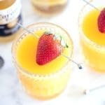 A bottle of corona and two beermosas topped with strawberries.