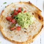 Close up of a Mulitas topped with guacamole and salsa.