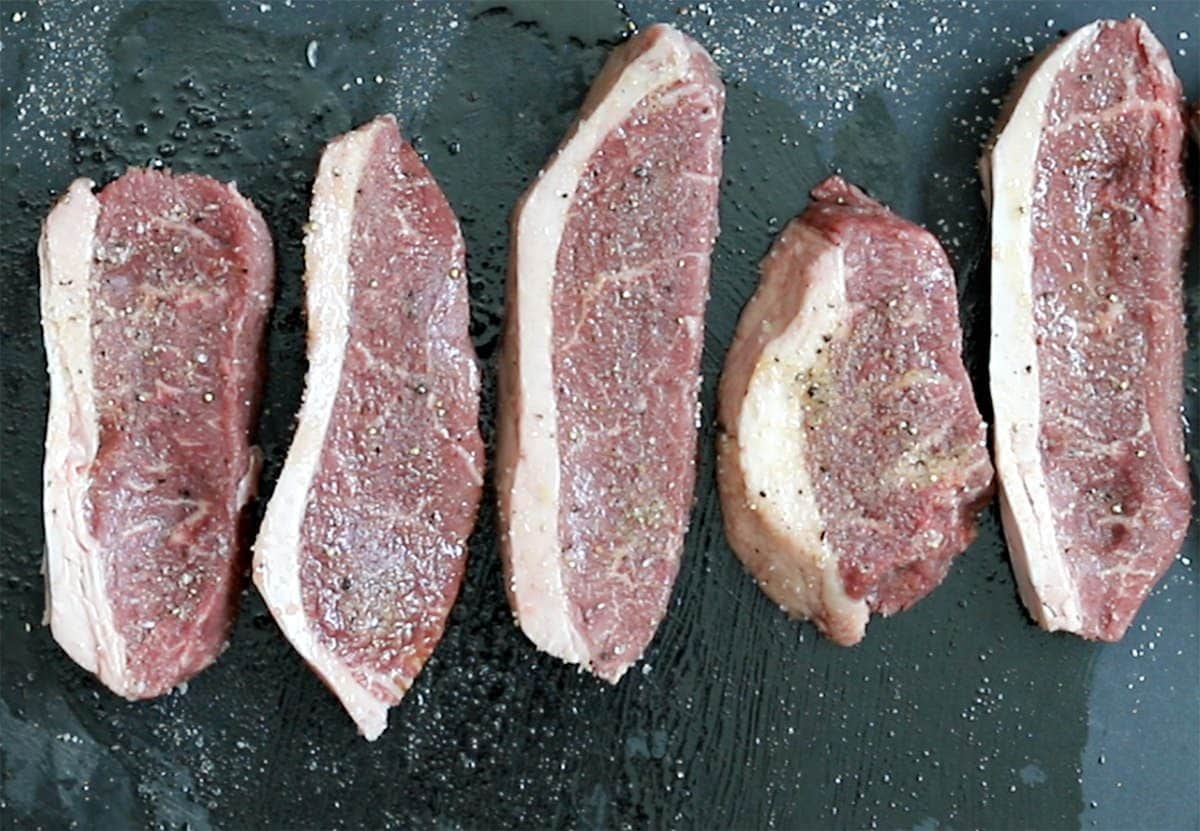 Cut coulotte steaks on a black cutting board.