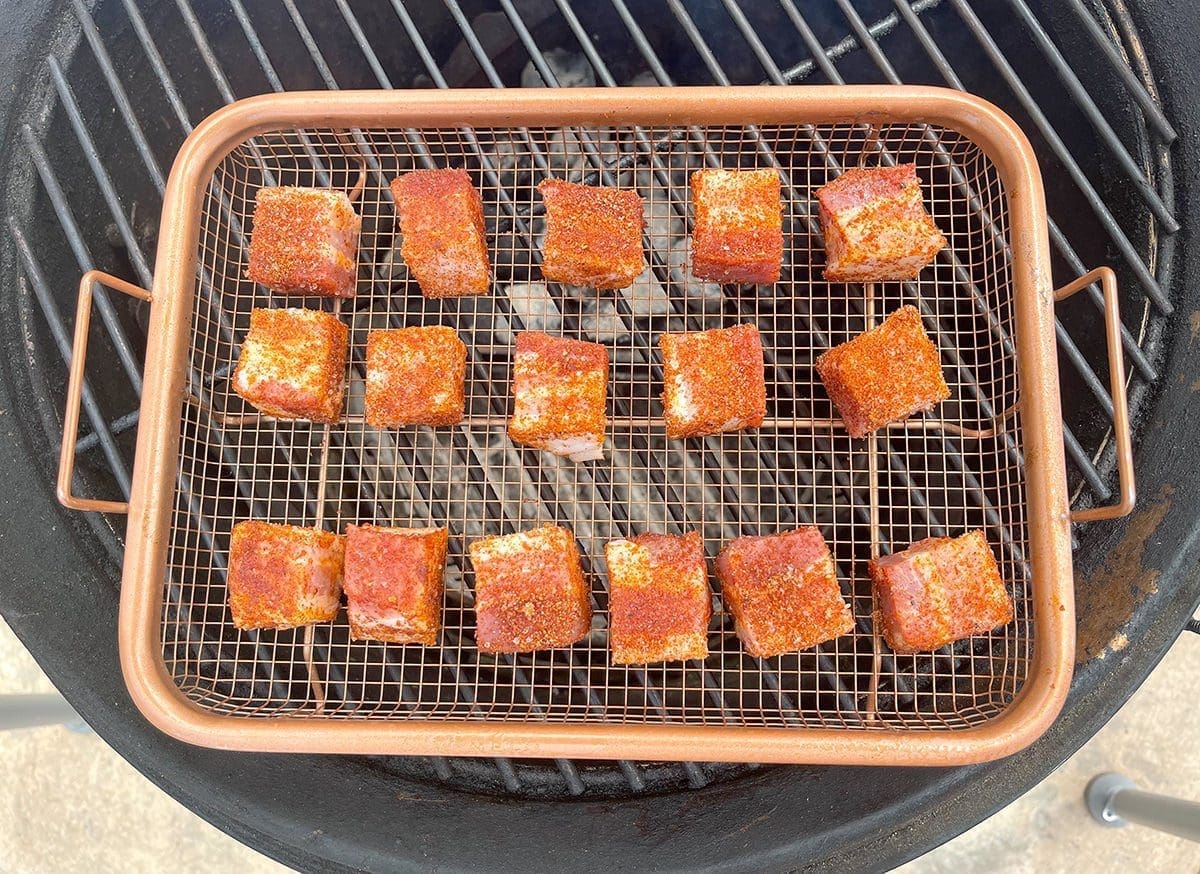 Pork belly cubes on a gold grill grate.