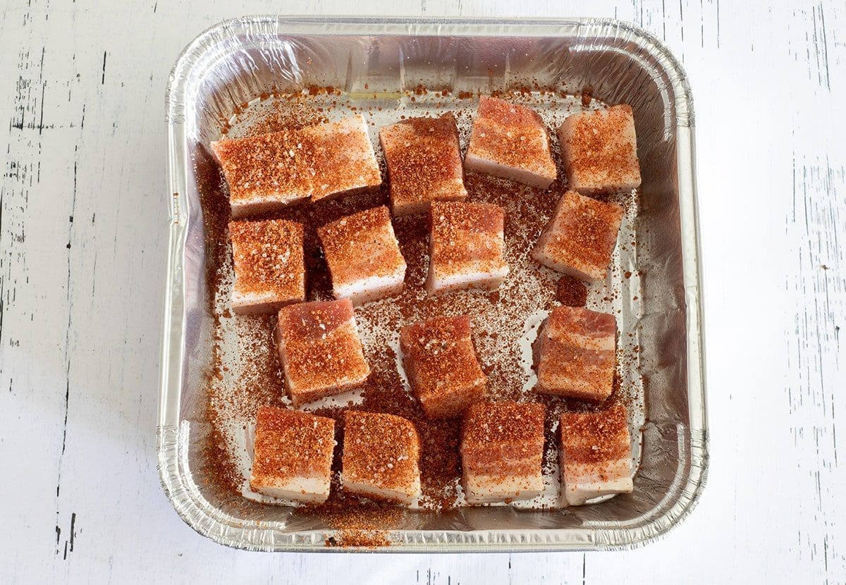 Pork cubes in a disposable aluminum pan.