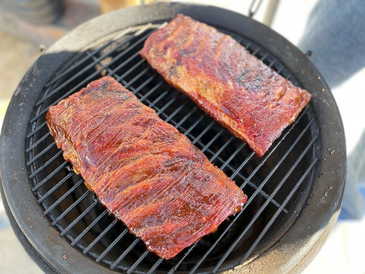 Two slabs of pork ribs on a smoker.