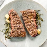Two Denver Steaks on a blue dinner plate.