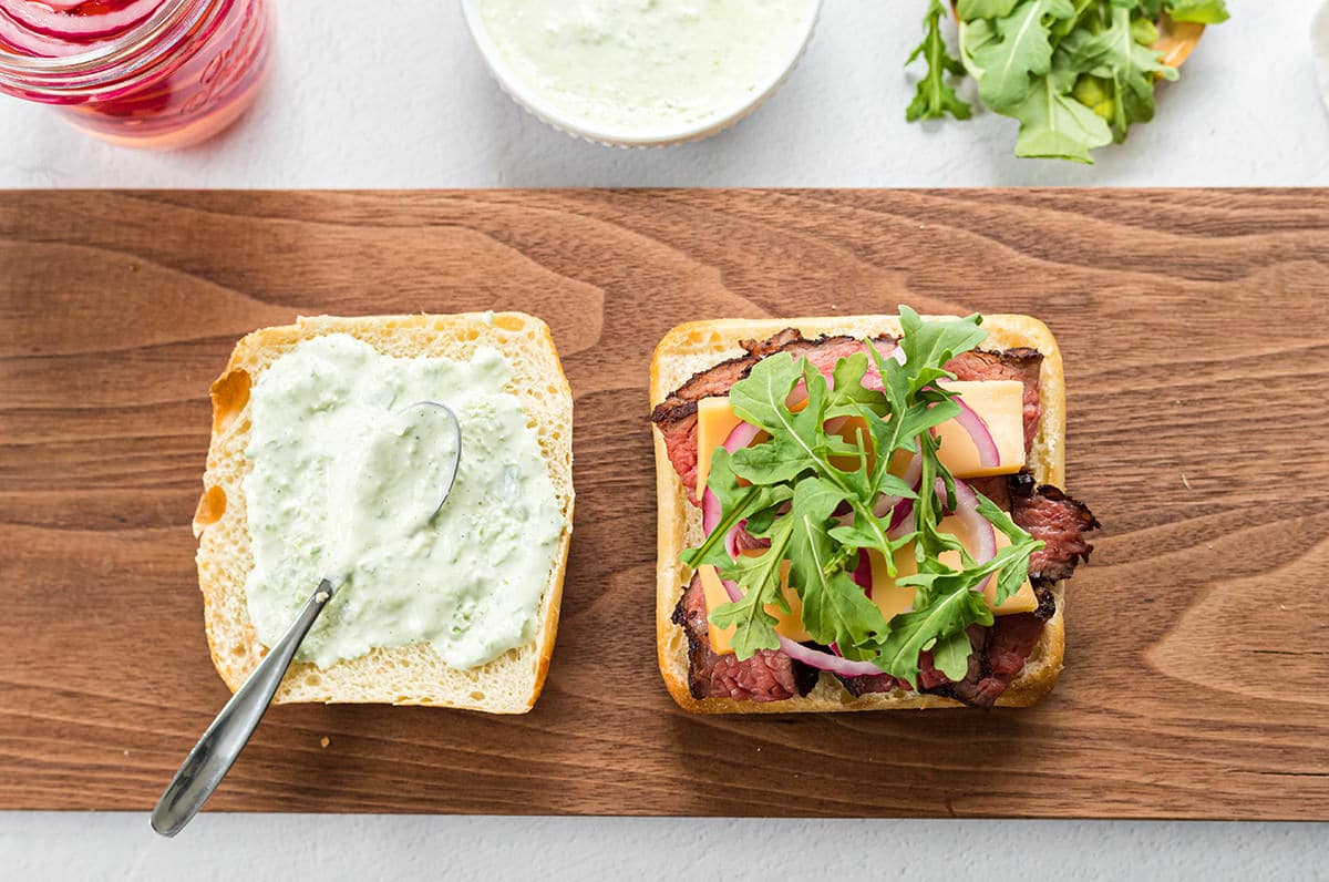 Open steak sandwich on a cutting board.