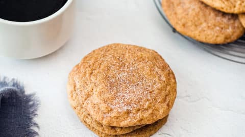 Stack of pumpkin snickerdoodles with a cup of coffee.