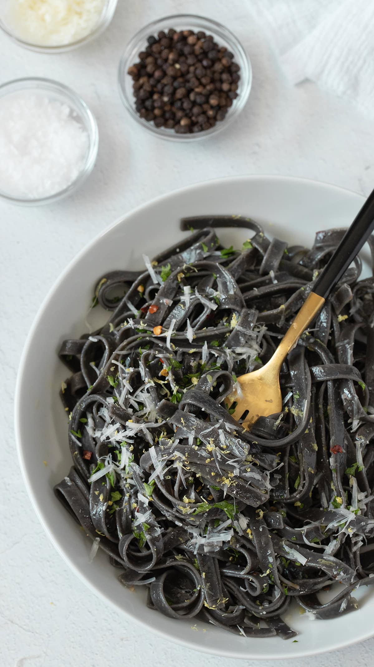 Bowl of squid ink spaghetti in a white bowl.