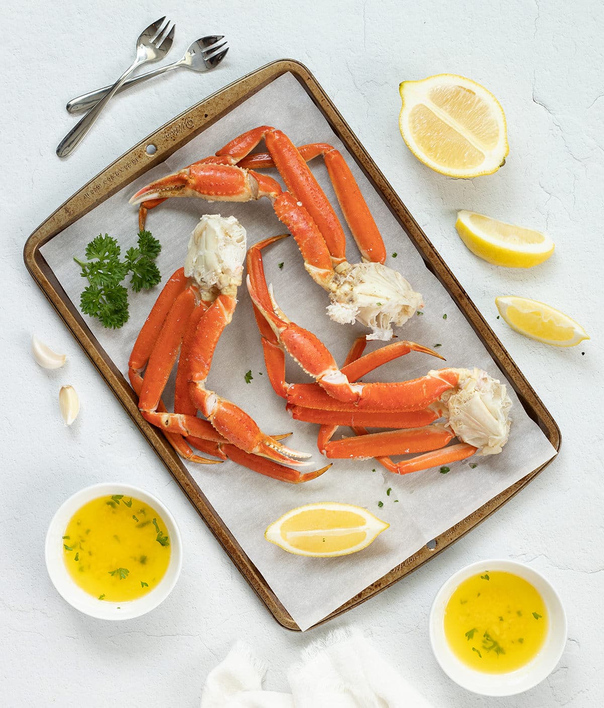 Crab legs on a baking sheet with garlic butter.