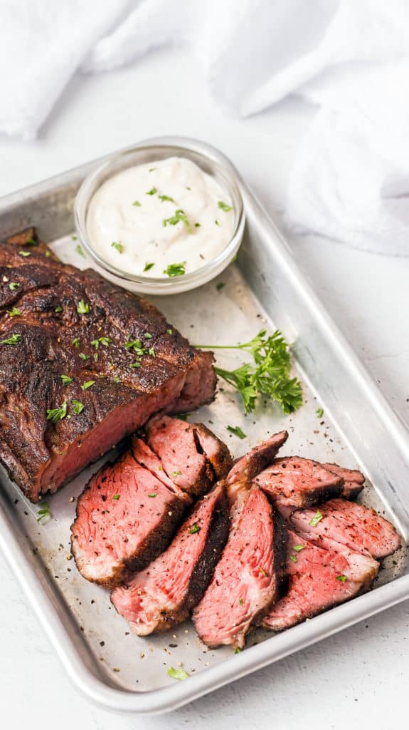 Sliced roast beef on a silver baking sheet.
