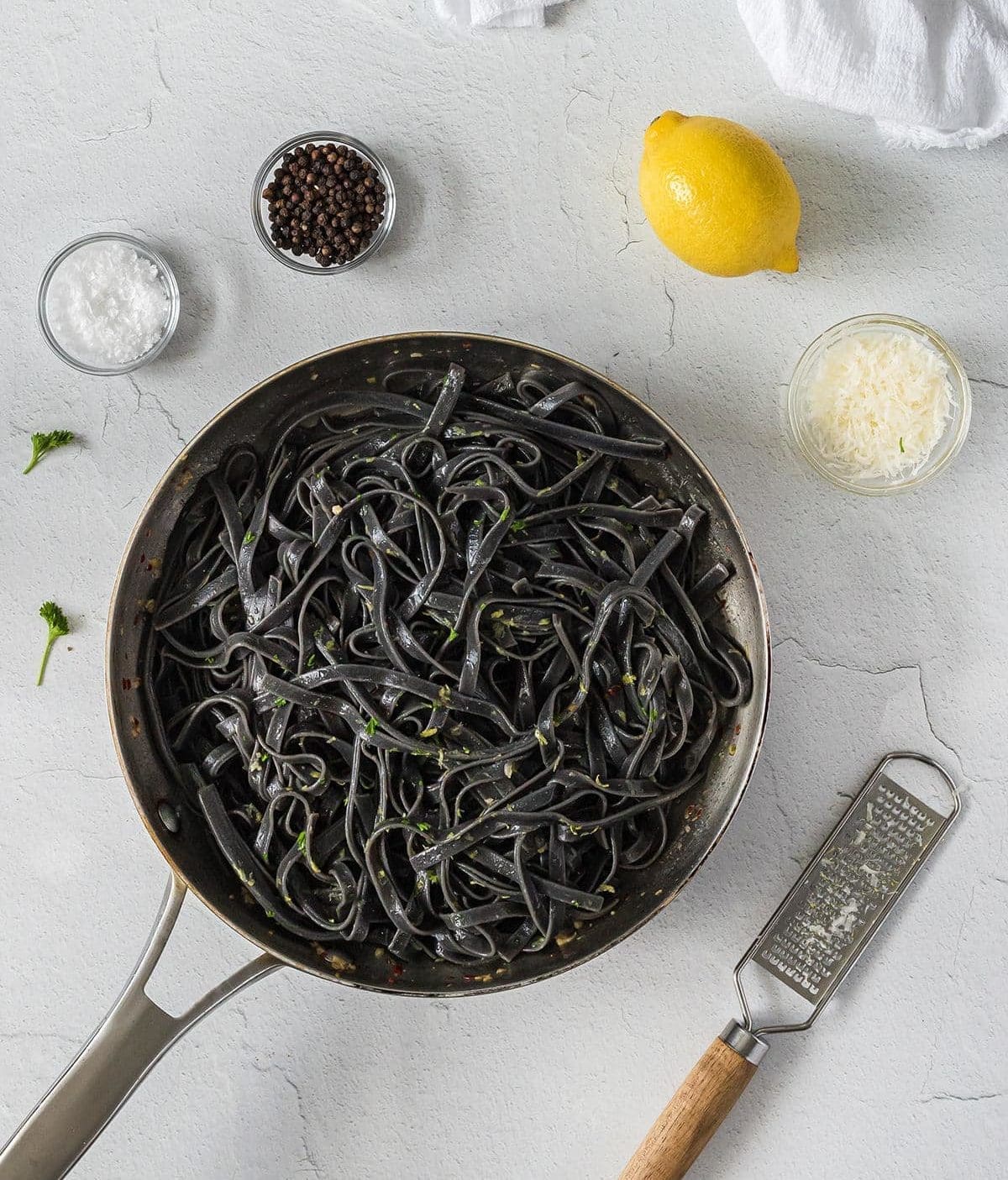 Silver skillet filled with cooked squid ink pasta.