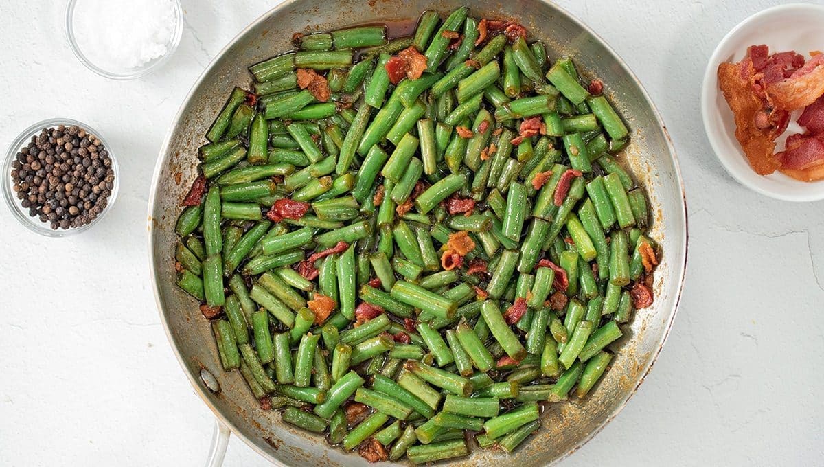 Crack green beans in a silver skillet.