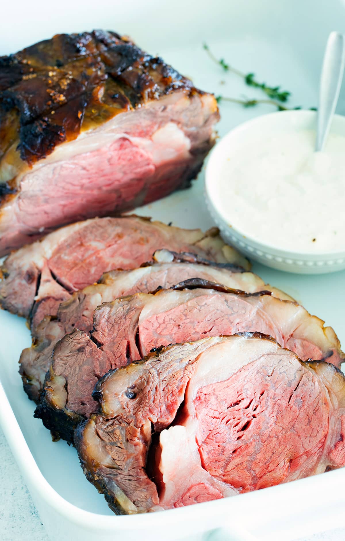 Sliced standing rib roast in a white pan.