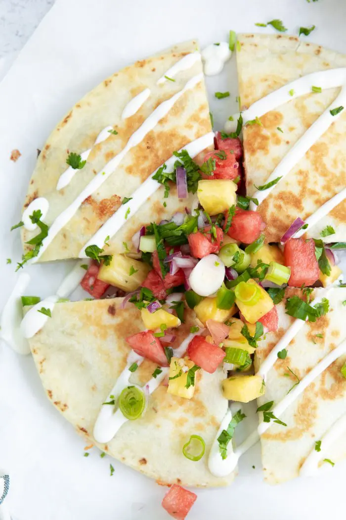 Quesadilla covered with pineapple salsa cut in 4 pieces.