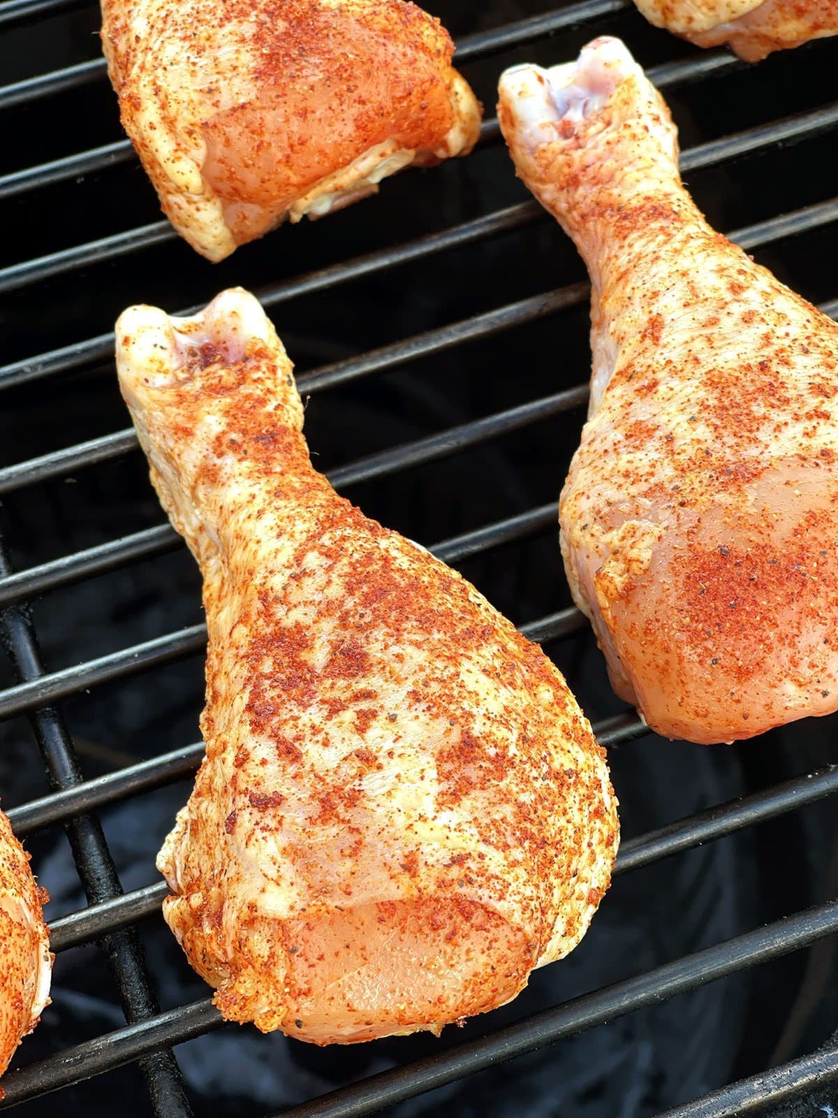 Close up of a chicken leg seasoning with BBQ rub.