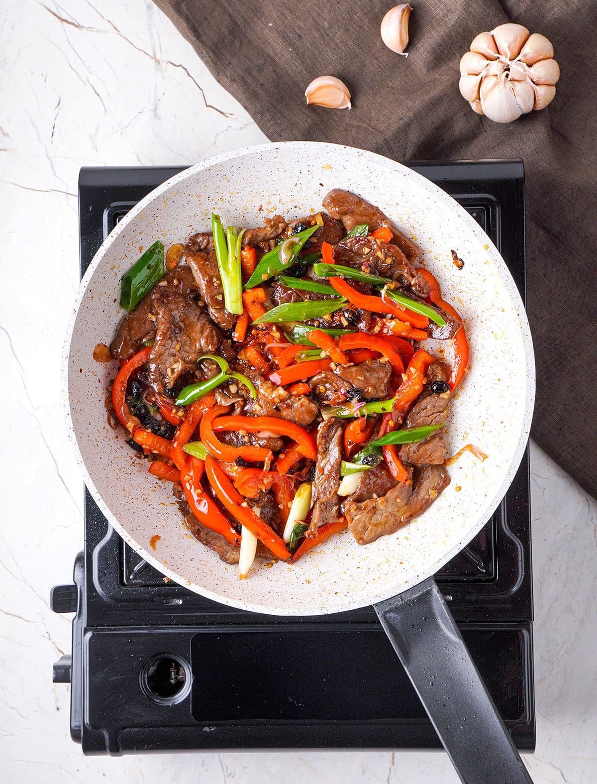 Beef stir fry in a white skillet.