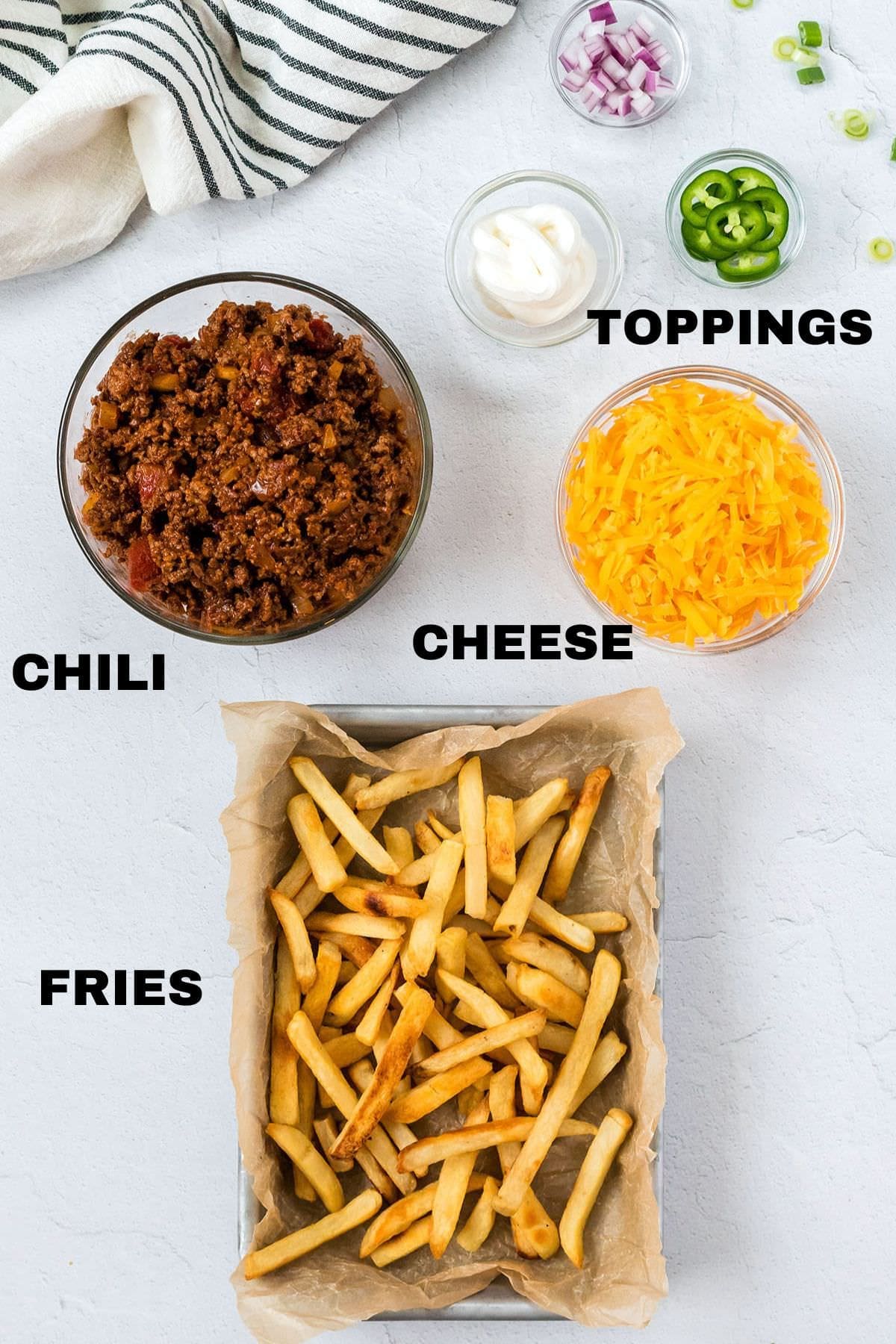 Sheet of frozen french fries along with a bowl of chili and cheese.