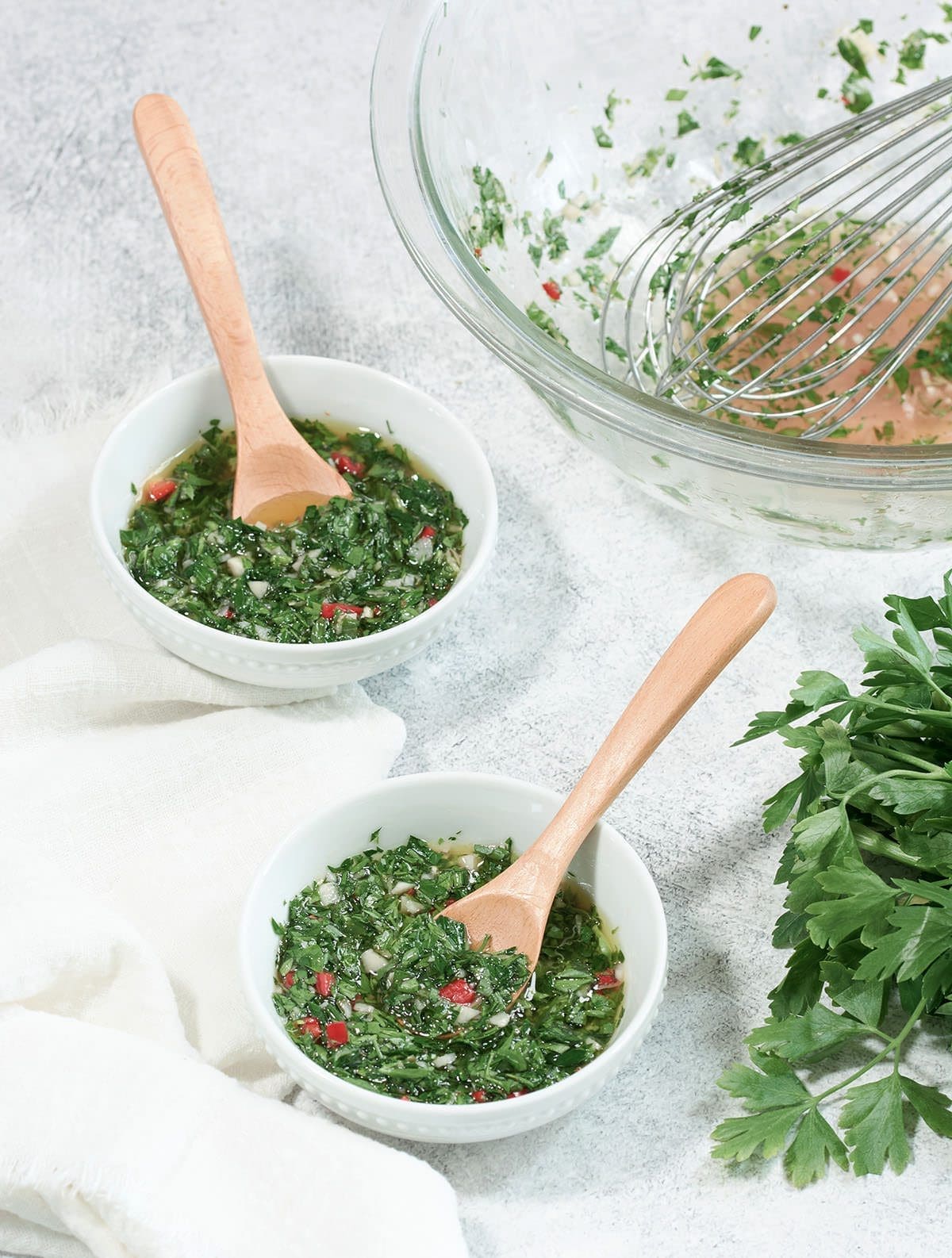 Two white bowls filled with chimichurri.