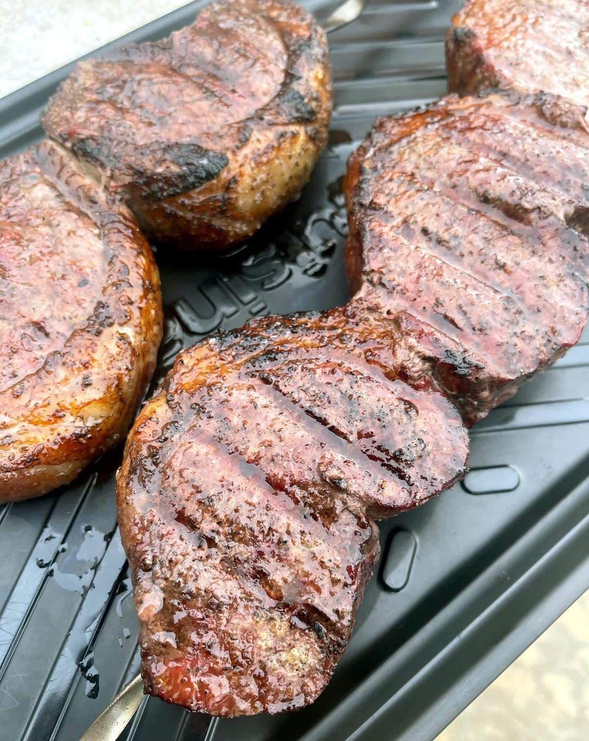 Cooked Picanha steak on a black platter.