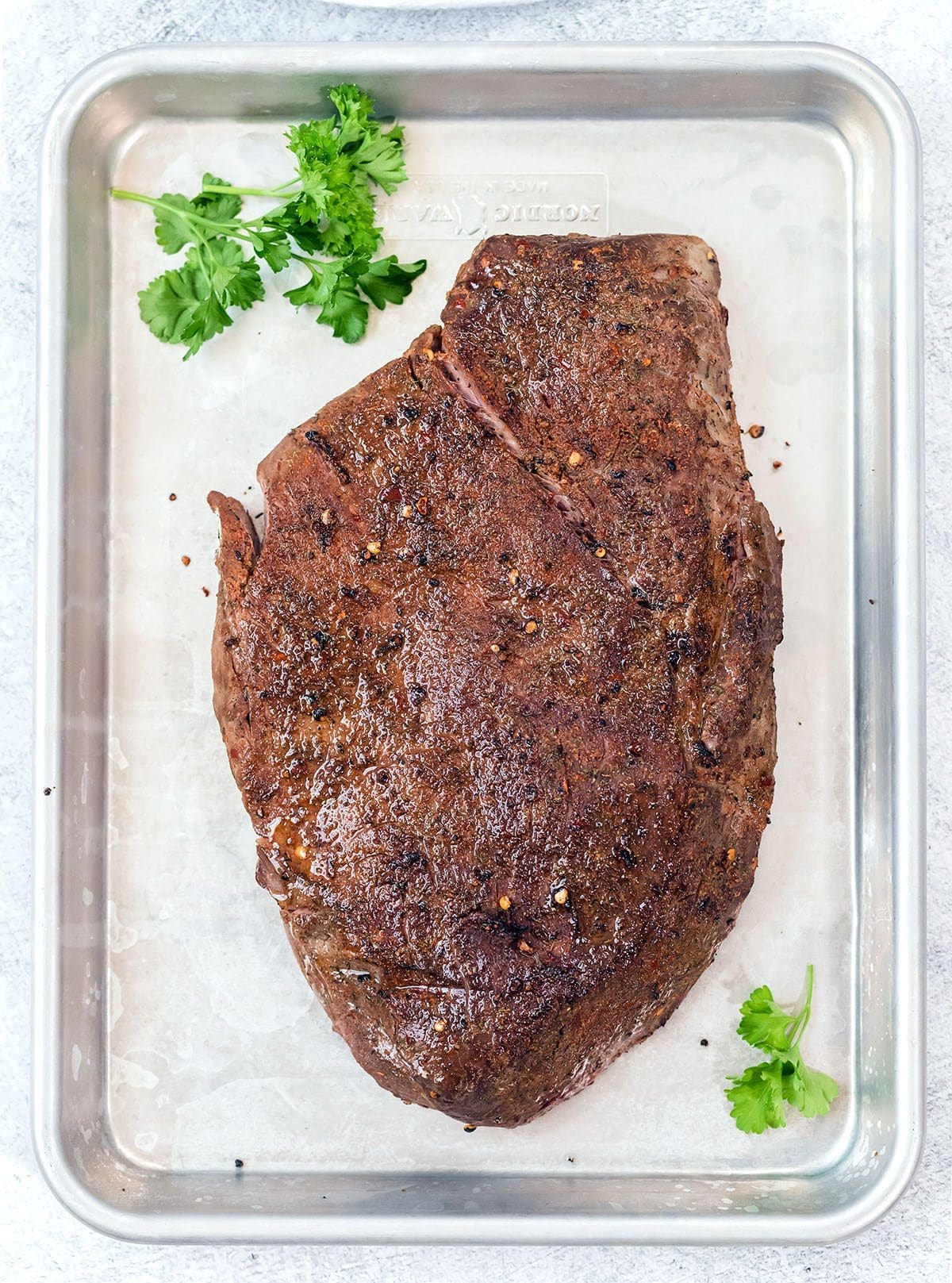 Cooked London Broil Roast on a silver baking sheet.