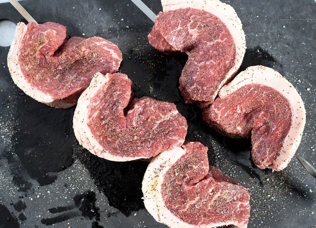 Slices of beef threaded on meat skewers.
