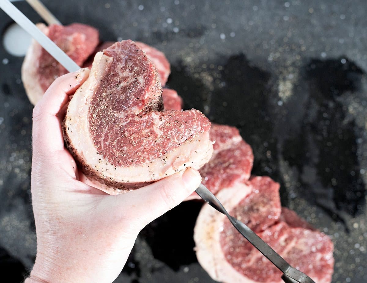Steak being squashed into an AC shape for threading onto a skewer.